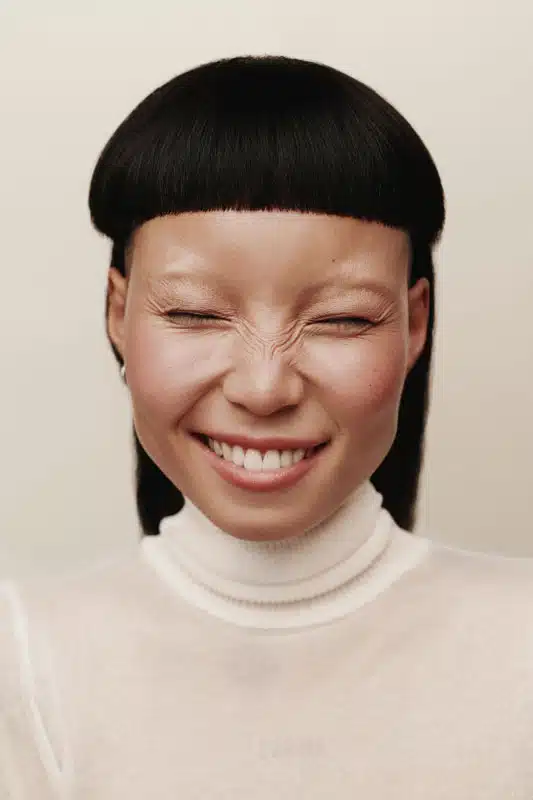 Smiling portrait with a blunt fringe and a turtleneck
